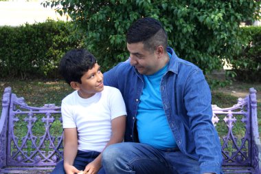 Boşanmış bekar bir baba, 10 yaşındaki esmer tenli Latin oğluyla bankta oturup Babalar Günü 'nü kutluyor.