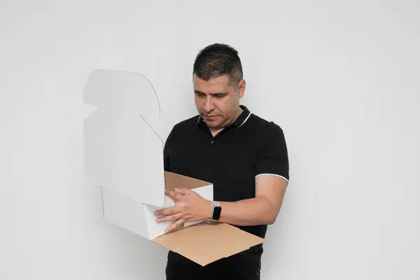 stock image Dark-skinned Latino adult man assembles a cardboard box following the instructions concentrated and attentive