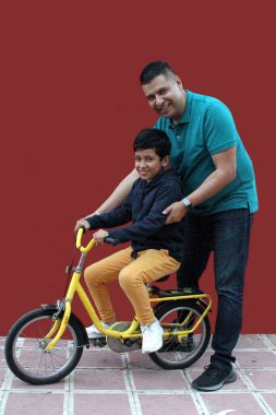 Boşanmış bekar baba, 9 yaşındaki kahverengi oğluna, baba-oğul aktivitesi olarak bisiklete binmeyi öğretiyor.