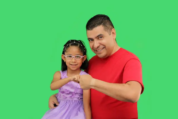stock image Divorced single dad with his brunette Latin daughter dressed in a princess dress in front of the green screen bumping fists