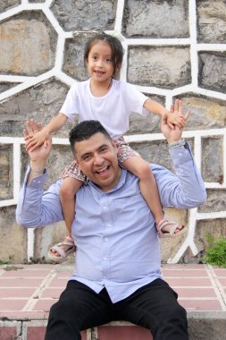 Boşanmış bekar baba, 5 yaşındaki Latin kızını sırtında taşıyor. Babalar Günü 'nü birlikte kutluyor ve eğleniyor.