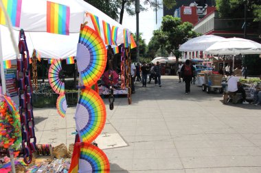 Mexico City, Mexico - 12 Haziran 2024: Gurur ayında yürüyüş için gey gökkuşağı bayraklı ürünler satan sokak tezgahı