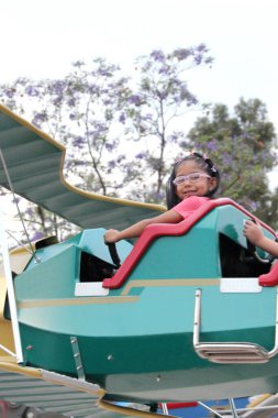 5 yaşındaki gözlüklü Latin esmer kız yaz tatilini eğlence parkında geçirerek eğleniyor.