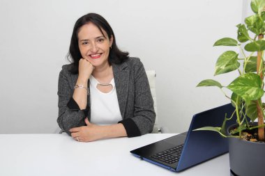 40 yaşında kadın ofiste dizüstü bilgisayarla çalışıyor ve müşteri hizmetlerinde yönetici ve satış uzmanı olarak çalışıyor.