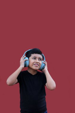 9 yaşındaki esmer tenli Latin çocuk, otizm ve dikkat eksikliği hiperaktivite bozukluğu nedeniyle gürültü yalıtımlı kulaklık kullanıyor.