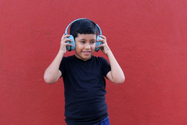 9 yaşındaki esmer tenli Latin çocuk, otizm ve dikkat eksikliği hiperaktivite bozukluğu nedeniyle gürültü yalıtımlı kulaklık kullanıyor.
