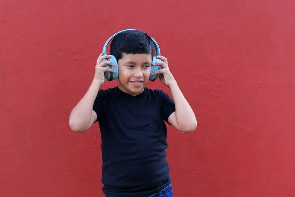 stock image 9-year-old dark-skinned Latino boy uses noise-isolating headphones due to the sensitivity caused by autism and attention deficit disorder ADHD