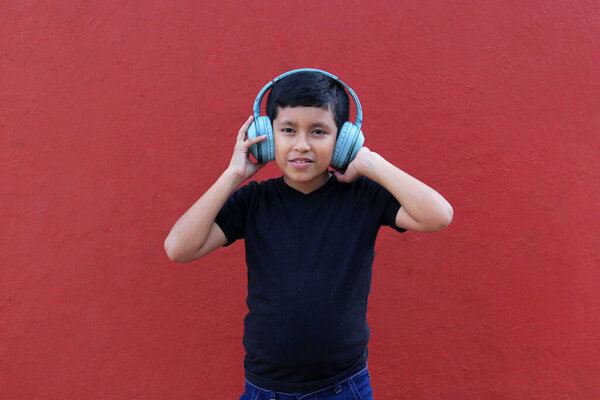 9-летний темнокожий латиноамериканец использует шумоизолирующие наушники из-за чувствительности, вызванной аутизмом и синдромом дефицита внимания СДВГ