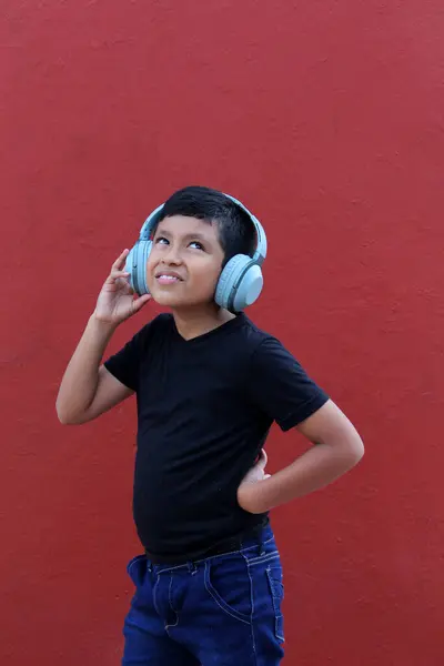 stock image 9-year-old dark-skinned Latino boy uses noise-isolating headphones due to the sensitivity caused by autism and attention deficit disorder ADHD