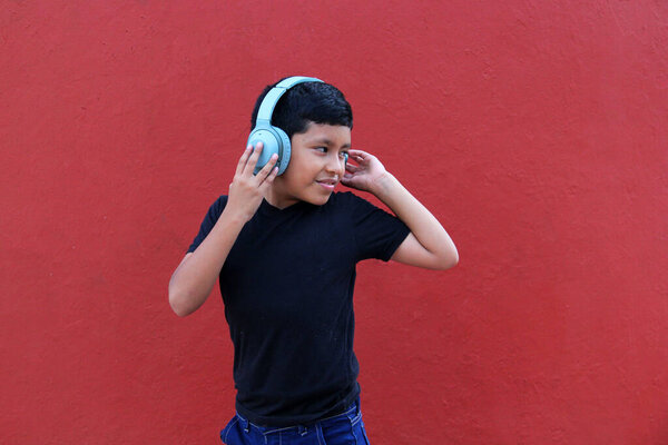 9-летний темнокожий латиноамериканец использует шумоизолирующие наушники из-за чувствительности, вызванной аутизмом и синдромом дефицита внимания СДВГ