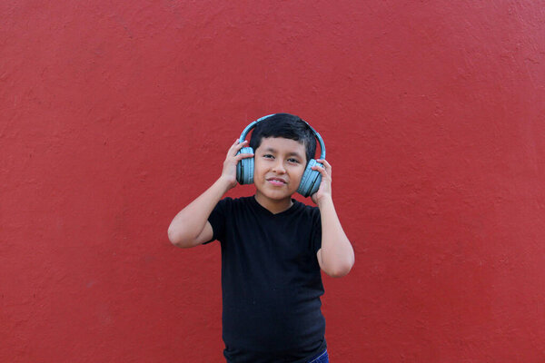 9-летний темнокожий латиноамериканец использует шумоизолирующие наушники из-за чувствительности, вызванной аутизмом и синдромом дефицита внимания СДВГ