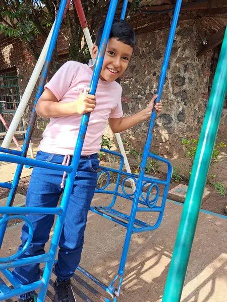 stock image 8-year-old dark-skinned Latino boy plays on the playground, swings on the swing, has fun in the park as therapy for attention deficit hyperactivity disorder ADHD