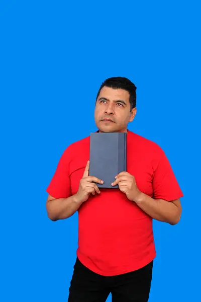 Stock image 40-year-old dark-skinned Latino man shows and reads a book as study and entertainment because he likes to learn