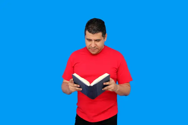 stock image 40-year-old dark-skinned Latino man shows and reads a book as study and entertainment because he likes to learn