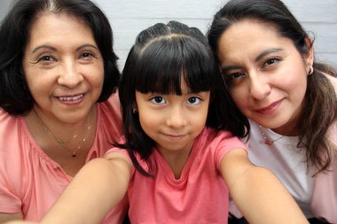 Üç nesil kadın büyükanne, anne ve esmer gözlüklü Latin kız sevgilerini gösterip anneler gününü kutluyorlar.