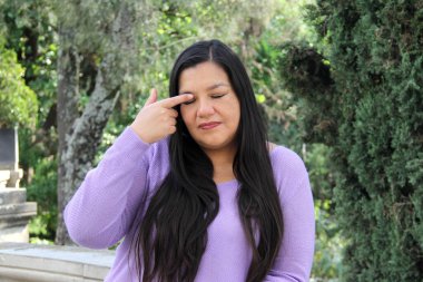 40-year-old Latin woman with long straight hair rubs her eyes because they burn and hurt due to allergies and pollution in the environment clipart