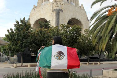 Latin yetişkin kadın Meksika Bağımsızlık Günü ve Cinco de Mayo bayramını kutlamak için Meksika bayrağını gururla gösteriyor.