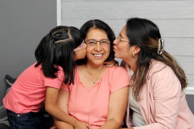 Esmer Latin büyükannesi kızı ve torunu tarafından şımartılıyor, birbirlerine destek olmak için bakıyorlar ve büyükanne ve büyükbabalar gününü kutluyorlar.