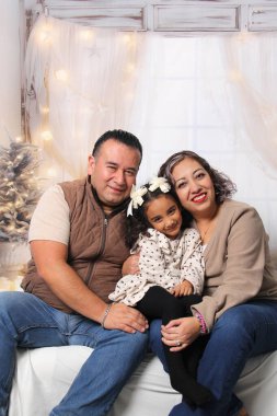 Baba, anne ve kızının koyu tenli Latin aileleri Noel ve yeni yılı kutlamak için sevgilerini ve öpücükleriyle gösterirler.