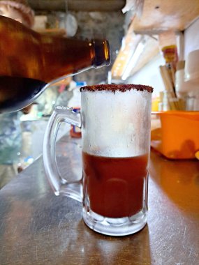 Dondurulmuş bir kavanozda limon, sos ve birayla servis edilen taze Meksika içeceği hazırlayan eller.