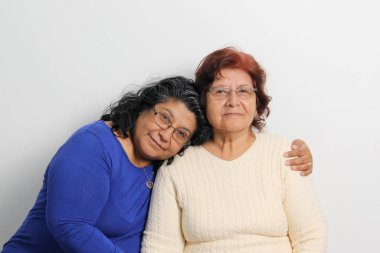 80 yaşındaki anne ve 50 yaşındaki esmer kız Latin sevgilerini gösterip Anneler Günü 'nü kutluyorlar.