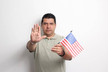 40 yaşında esmer tenli Latin bir adam Amerika topraklarında göçmen olarak yaşayan Amerika Birleşik Devletleri bayrağını gösteriyor.