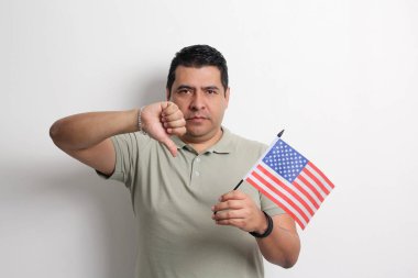 40 yaşında esmer tenli Latin bir adam Amerika topraklarında göçmen olarak yaşayan Amerika Birleşik Devletleri bayrağını gösteriyor.