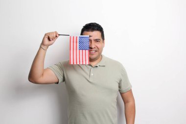 40 yaşında esmer tenli Latin bir adam Amerika topraklarında göçmen olarak yaşayan Amerika Birleşik Devletleri bayrağını gösteriyor.
