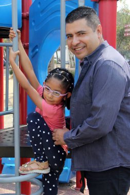 Boşanmış bekar baba ve 5 yaşındaki esmer Latin kızı park oyunlarında oynuyorlar ve dışarıda kaliteli zaman geçiriyorlar.