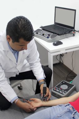 Koyu tenli Latin nörolog, elektromiyografi ve somatosensoriyel potansiyel çalışma yapıyor.