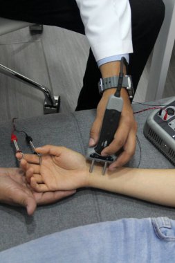 Uzman bir doktorun elleri, ağrı ve hareket sorunu olan bir hastada nörolojik çalışma elektromiyografisi ve somatosensoriyel canlandırma potansiyelleri gerçekleştirir.