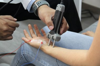 Uzman bir doktorun elleri, ağrı ve hareket sorunu olan bir hastada nörolojik çalışma elektromiyografisi ve somatosensoriyel canlandırma potansiyelleri gerçekleştirir.