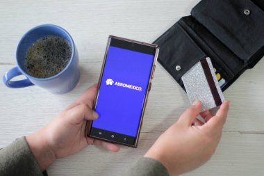 Mexico City, Mexico - 22 Şubat 2025: Aeromexico Havayolları 'nın seyahat biletlerinizi ayırtmak ve giriş kartınızı almak için cep telefonu ve bilgisayar başvurusu