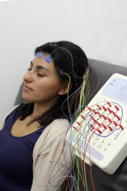 20 yaşındaki Latin esmer kadın epilepsi teşhisi koymak için kablolar ve elektrotlarla EEG elektroansefalogramına tabi tutuluyor.