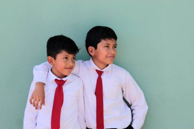 8 ve 10 yaşlarında okul üniforması giyen Latin çocuklar okula dönmekten mutlu ve heyecanlılar.