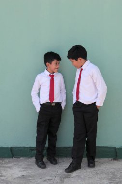 8 ve 10 yaşlarında okul üniforması giyen Latin çocuklar okula dönmekten mutlu ve heyecanlılar.