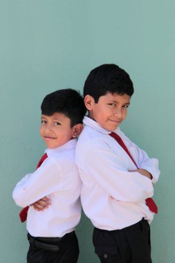 8 ve 10 yaşlarında okul üniforması giyen Latin çocuklar okula dönmekten mutlu ve heyecanlılar.