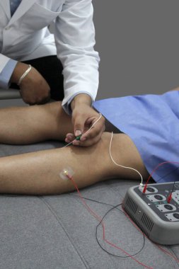 Nöroloğun ofisindeki genç bir hastanın bacaklarında elektromiyografi ve somatosensyon potansiyelleri var.