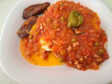Huevos motulenos, Meksika 'nın Yucatan kentindeki Motul kasabasından tipik bir kahvaltı yemeğidir. Kızarmış tortilla, fasulye, kızarmış yumurta, domates sosu, jambon, bezelye ve habanero biberinden oluşur.