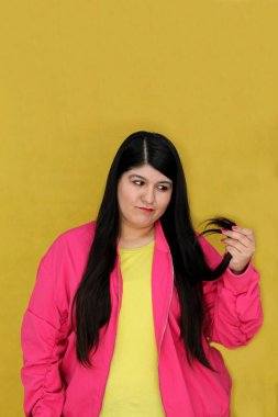 Uzun düz saçlı, 30 yaşındaki Latin bir kadın kuru, hasarlı saçları ve kırık uçlarıyla tatmin olmuyor ve hayal kırıklığına uğruyor.