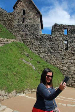 30 yaşındaki Latin bir kadın Cusco, Peru 'daki Machu Picchu arkeolojik alanını keşfediyor, selfie çekiyor ve turist olarak tatilinin tadını çıkarıyor.