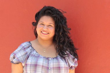 25 yaşında kıvırcık saçlı ve çalışan esmer bir kadın mutlu, güçlü, bağımsız ve güçlü görünüyor.