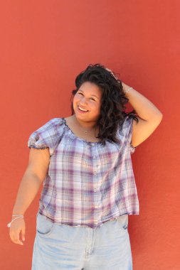 25 yaşında kıvırcık saçlı ve çalışan esmer bir kadın mutlu, güçlü, bağımsız ve güçlü görünüyor.