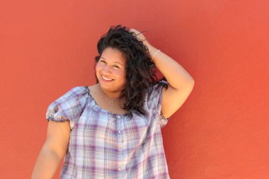 25 yaşında kıvırcık saçlı ve çalışan esmer bir kadın mutlu, güçlü, bağımsız ve güçlü görünüyor.