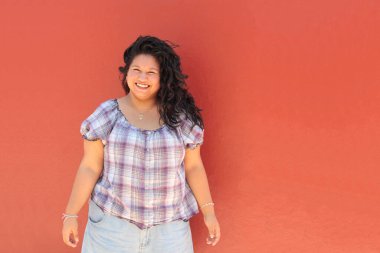 25 yaşında kıvırcık saçlı ve çalışan esmer bir kadın mutlu, güçlü, bağımsız ve güçlü görünüyor.