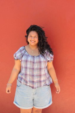 25 yaşında kıvırcık saçlı ve çalışan esmer bir kadın mutlu, güçlü, bağımsız ve güçlü görünüyor.