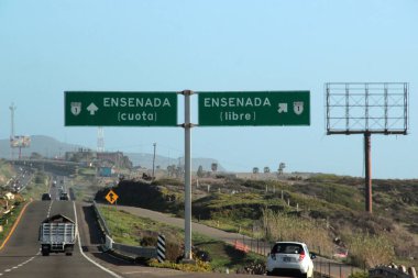 Ensenada, Baja California, Meksika - 14 Aralık 2025: Meksika 'da Tijuana' dan Ensenada Baja California 'ya giden Panoramik Karayolu üzerindeki yol işaretleri yön ve mesafeyi veya çıkışları gösteriyor
