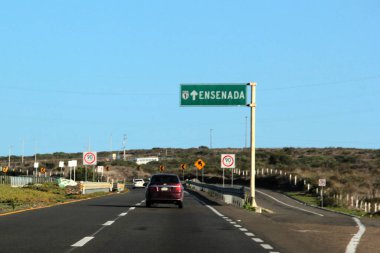 Ensenada, Baja California, Meksika - 14 Aralık 2025: Meksika 'da Tijuana' dan Ensenada Baja California 'ya giden Panoramik Karayolu üzerindeki yol işaretleri yön ve mesafeyi veya çıkışları gösteriyor