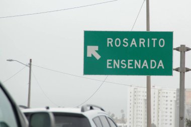 Ensenada, Baja California, Meksika - 14 Aralık 2025: Meksika 'da Tijuana' dan Ensenada Baja California 'ya giden Panoramik Karayolu üzerindeki yol işaretleri yön ve mesafeyi veya çıkışları gösteriyor