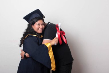 Esmer, kep ve cübbe giymiş Latin kızı ile gururlu ve tatmin olmuş bekar babası, okulun sonunu kutluyor.